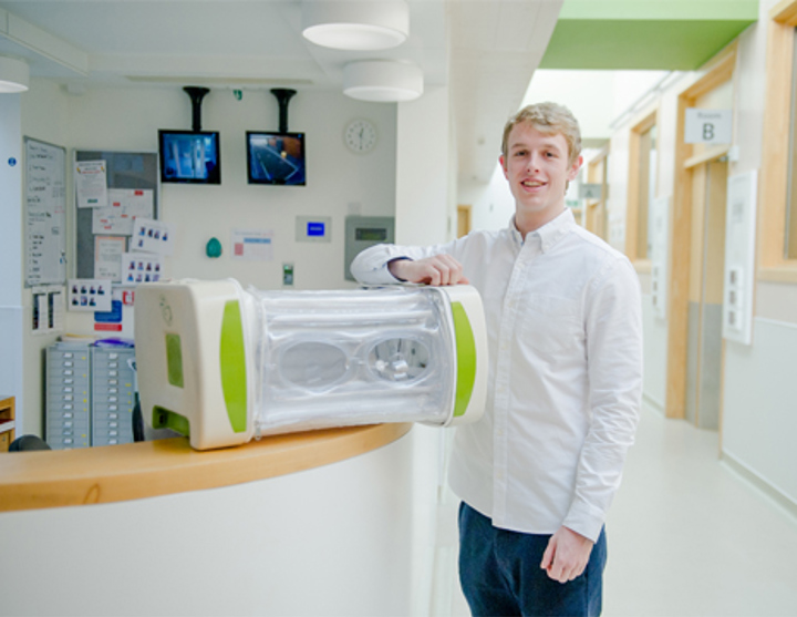 An image of the inventor of MOM in a hospital corridor. He is standing next to a MOM device.